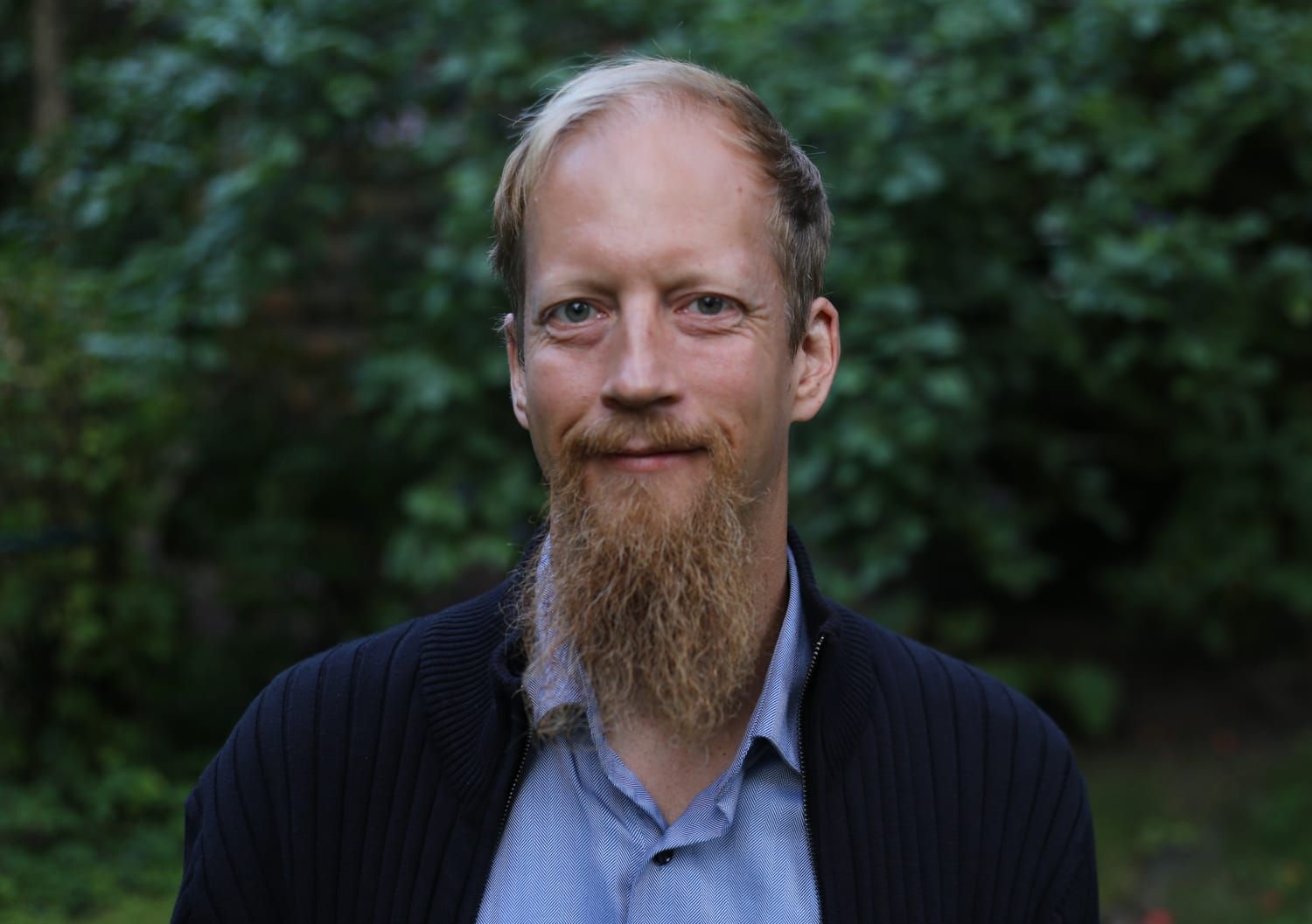 Juuso Kangas, taustalla vihreää lehvästöä.